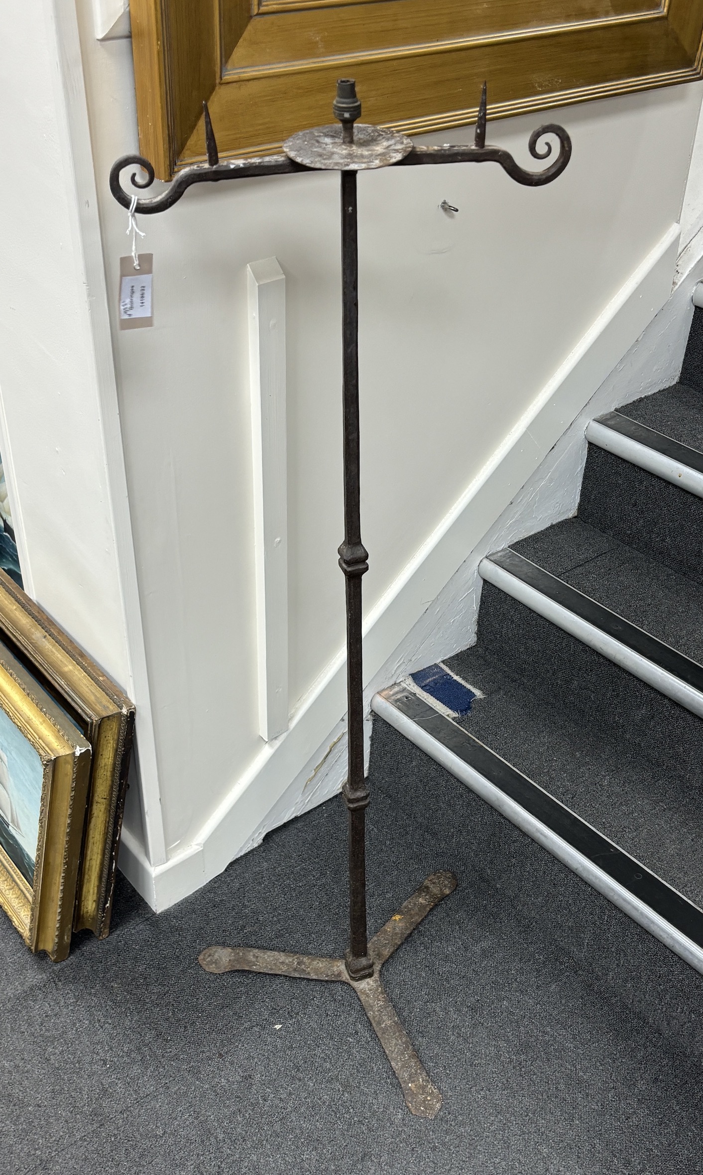A wrought iron twin branch floor standing candelabra, height 128cm, Provenance- Brede Place, East Sussex, a former residence of the Frewen family from 1712-1936.